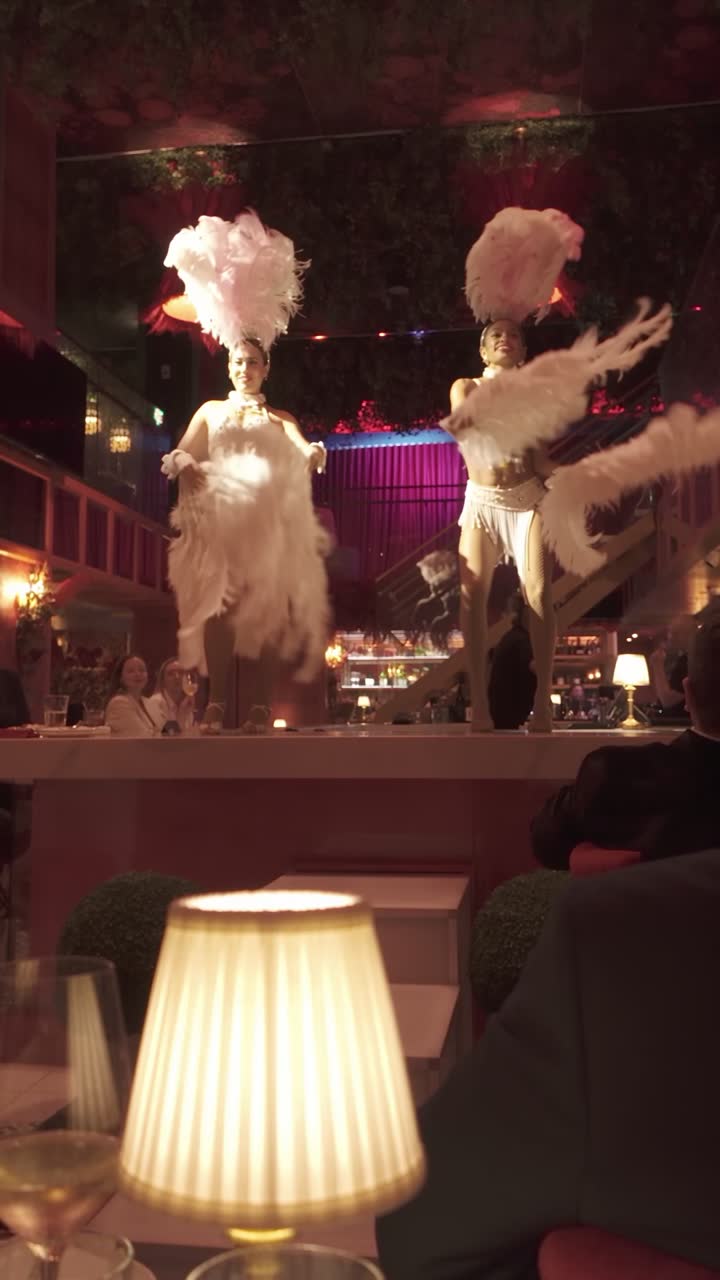 Bailarinas con abanicos de plumas junto a una mesa en J'Adore